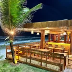 Ambiente do Bar Muah com mesas e cadeiras rústicas feitas em madeira de demolição