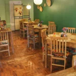 Conjunto com mesa de jantar 80 cm e cadeiras ripadas modelo Estação em madeira de demolição, ideal para ambientes pequenos de restaurante ou bistrô com estilo rústico