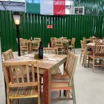 Conjunto de mesas e cadeiras coloridas feitas em madeira de demolição, trazendo alegria e rusticidade para o ambiente gastronômico